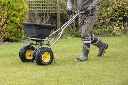 technician spreading lawn fertilizer